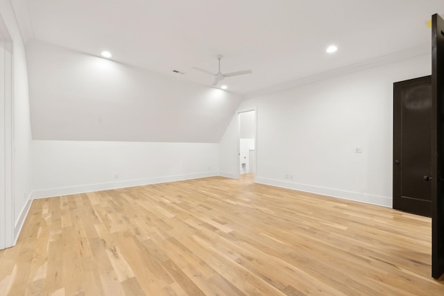 spare room with ceiling fan, ornamental molding, vaulted ceiling, and light wood-type flooring