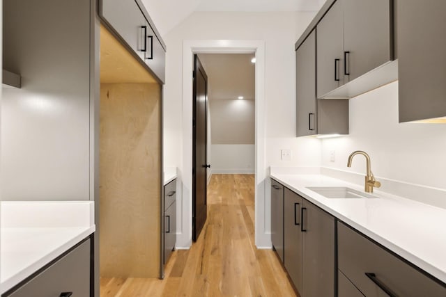 kitchen with sink, light hardwood / wood-style flooring, gray cabinets, and lofted ceiling