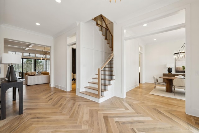 entrance foyer with ornamental molding, a notable chandelier, and parquet floors