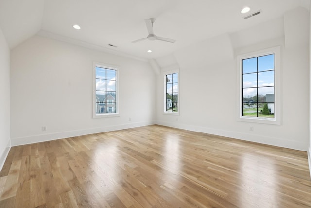 empty room featuring ceiling fan, a healthy amount of sunlight, vaulted ceiling, and light hardwood / wood-style floors