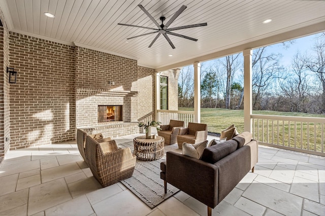 view of patio with ceiling fan and an outdoor living space with a fireplace