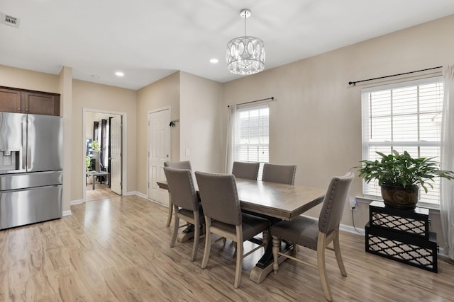 dining area featuring a wealth of natural light, a chandelier, and light wood-type flooring