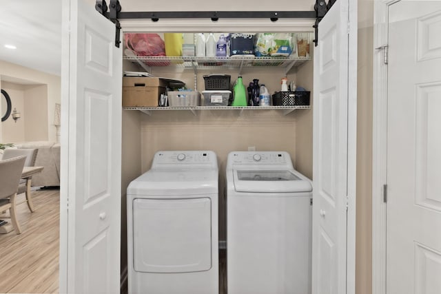 clothes washing area with light wood-type flooring and washing machine and clothes dryer