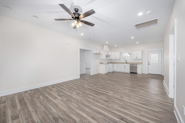 unfurnished living room featuring ceiling fan, sink, and light hardwood / wood-style floors