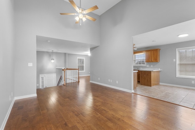 unfurnished living room featuring high vaulted ceiling, light hardwood / wood-style flooring, and ceiling fan