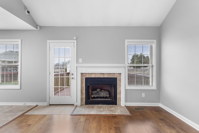 unfurnished living room featuring hardwood / wood-style floors, lofted ceiling, and a fireplace