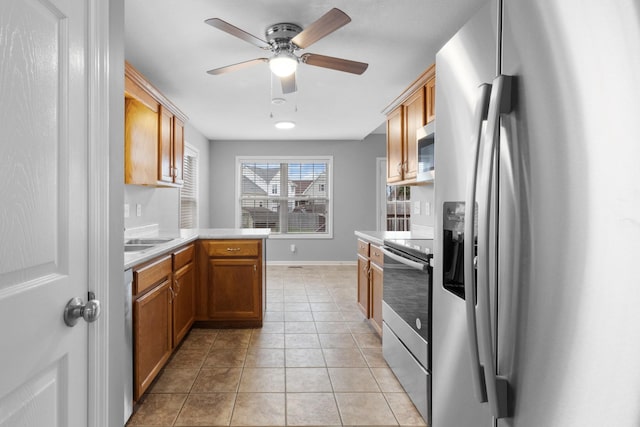 kitchen featuring kitchen peninsula, appliances with stainless steel finishes, light tile patterned floors, and ceiling fan