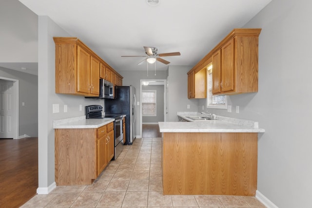 kitchen featuring kitchen peninsula, stainless steel appliances, ceiling fan, sink, and light tile patterned flooring