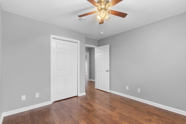 unfurnished bedroom with ceiling fan, dark hardwood / wood-style floors, and a closet