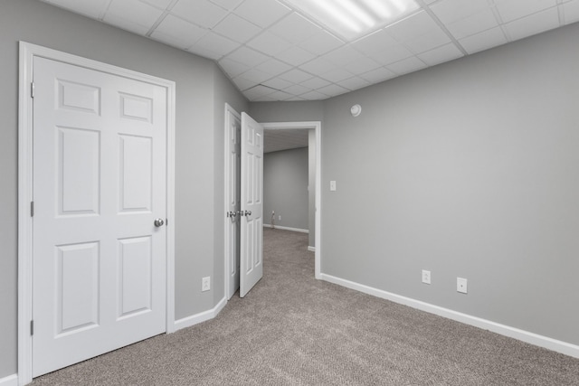 unfurnished bedroom with a drop ceiling and light colored carpet