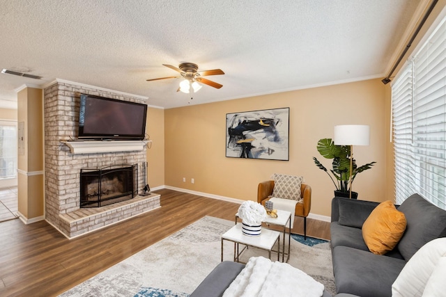 living room with hardwood / wood-style flooring, a fireplace, crown molding, and a textured ceiling