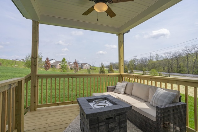 wooden deck with ceiling fan, a yard, and an outdoor living space with a fire pit