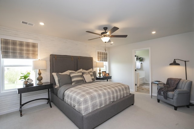 bedroom with light carpet, ensuite bath, and ceiling fan