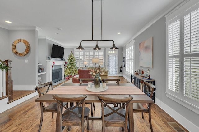 dining space featuring wood-type flooring and ornamental molding