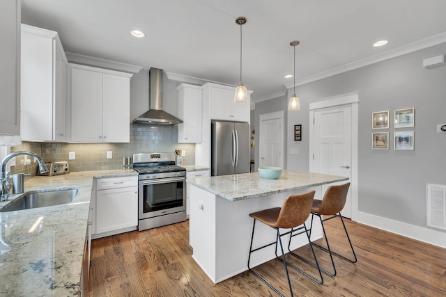 kitchen featuring wall chimney exhaust hood, stainless steel appliances, sink, a center island, and white cabinetry