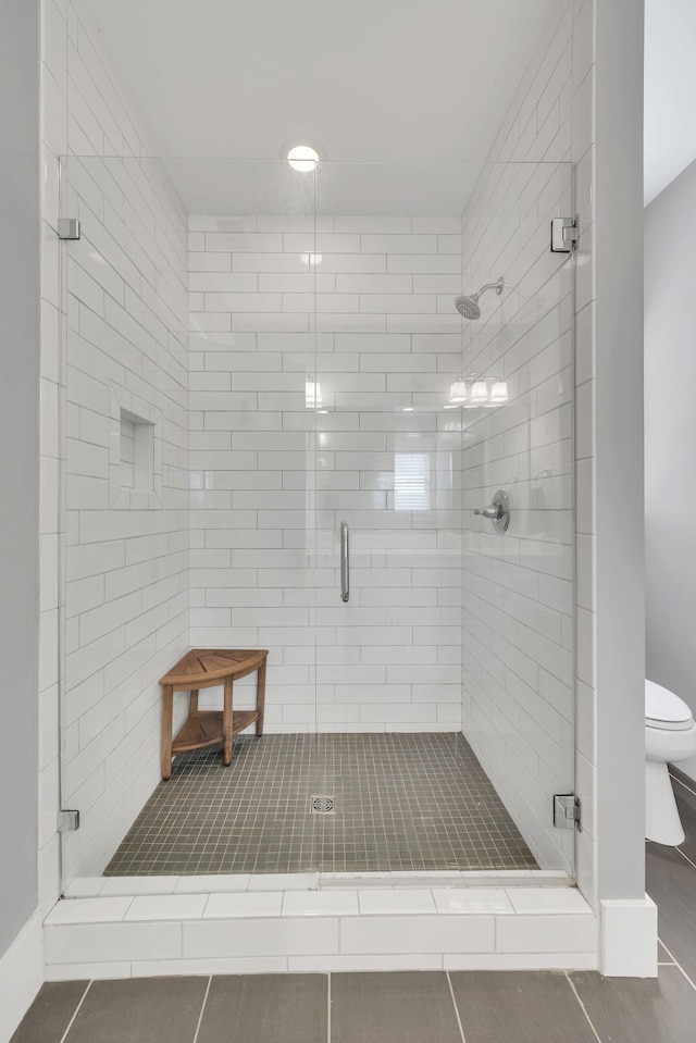 bathroom with tile patterned flooring, toilet, and an enclosed shower