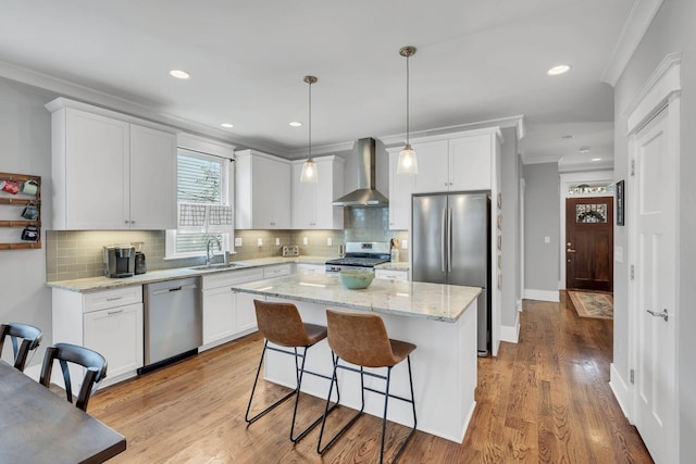 kitchen with white cabinetry, a center island, wall chimney exhaust hood, light hardwood / wood-style floors, and appliances with stainless steel finishes