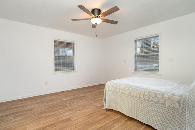 bedroom featuring ceiling fan, light wood-type flooring, and multiple windows