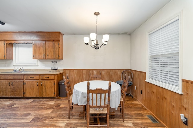 dining space featuring a notable chandelier, wood walls, dark hardwood / wood-style flooring, and sink