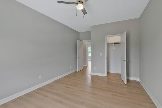 unfurnished bedroom with ceiling fan, light wood-type flooring, a spacious closet, and a closet