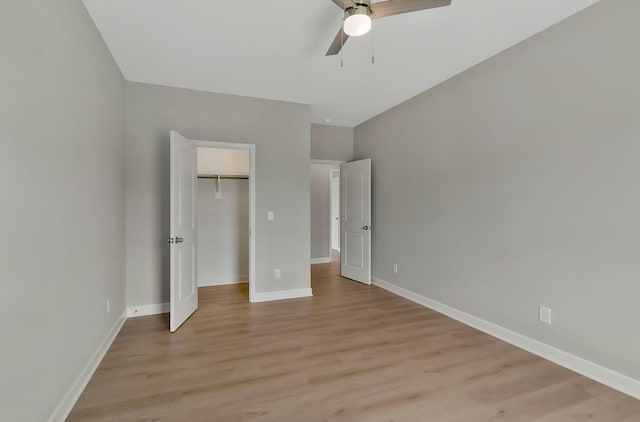 unfurnished bedroom featuring a spacious closet, ceiling fan, a closet, and light hardwood / wood-style floors