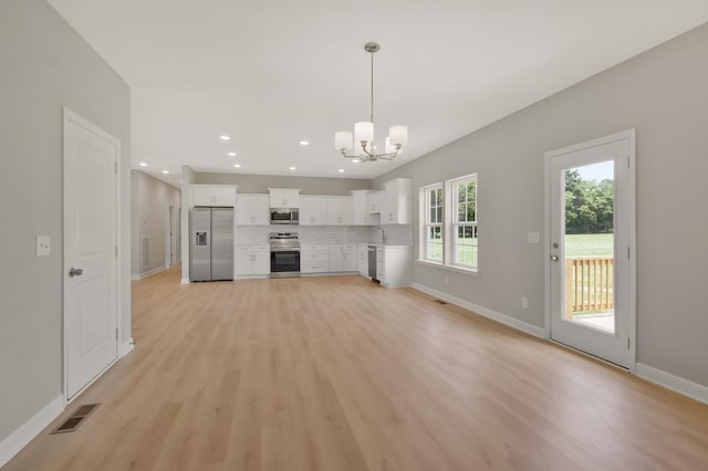 unfurnished living room featuring a chandelier and light hardwood / wood-style floors