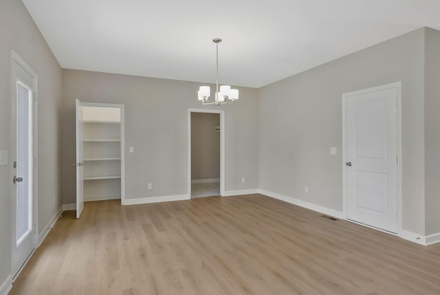 empty room with a chandelier and light hardwood / wood-style floors