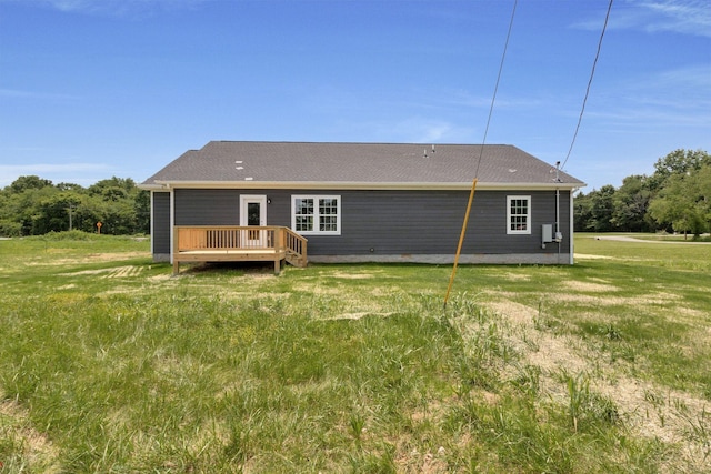 rear view of property with a wooden deck and a lawn