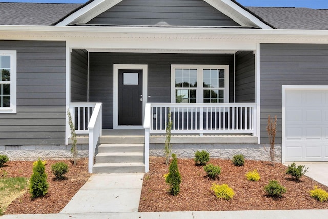 view of exterior entry featuring a garage and covered porch