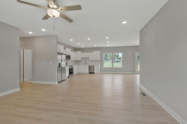 unfurnished living room featuring ceiling fan, sink, and light hardwood / wood-style flooring