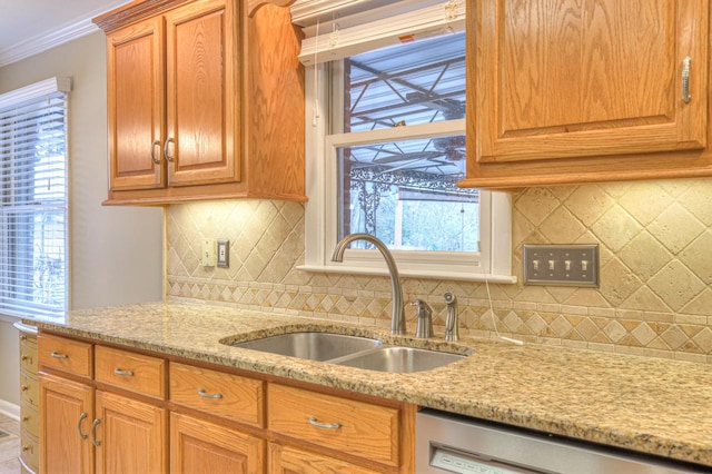 kitchen featuring decorative backsplash, light stone counters, stainless steel dishwasher, ornamental molding, and sink