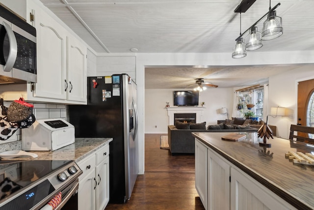 kitchen with decorative light fixtures, decorative backsplash, white cabinets, appliances with stainless steel finishes, and ceiling fan