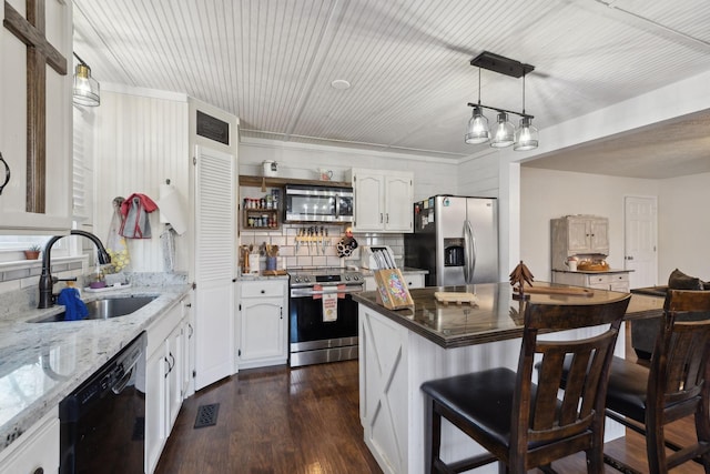 kitchen featuring hanging light fixtures, a breakfast bar area, appliances with stainless steel finishes, white cabinetry, and sink