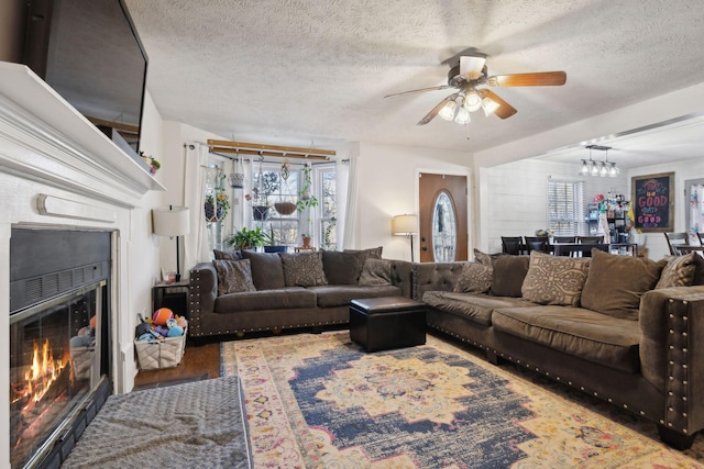 living room with ceiling fan with notable chandelier, hardwood / wood-style flooring, and a textured ceiling