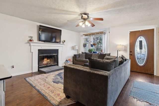 living room with a textured ceiling, ceiling fan, and dark hardwood / wood-style floors