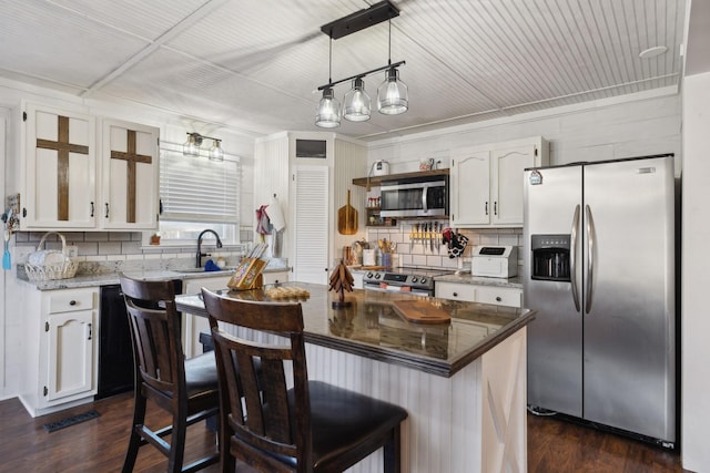 kitchen with dark wood-type flooring, pendant lighting, stainless steel appliances, a breakfast bar, and white cabinetry