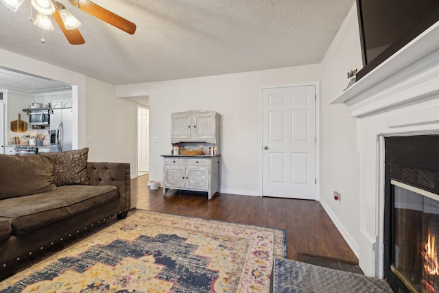 living room featuring a textured ceiling, ceiling fan, and dark hardwood / wood-style floors