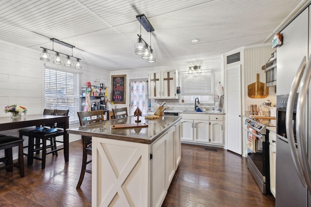 kitchen featuring white cabinets, a center island, pendant lighting, a breakfast bar, and appliances with stainless steel finishes