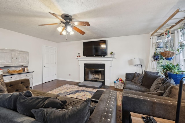 living room featuring a textured ceiling, ceiling fan, and dark wood-type flooring