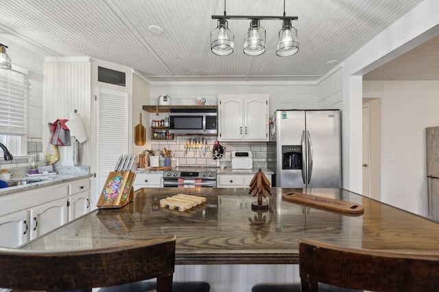 kitchen with stainless steel appliances, sink, white cabinets, light stone countertops, and pendant lighting