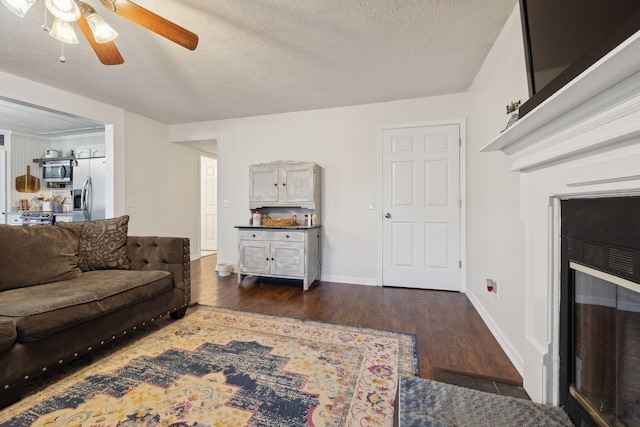 living room featuring dark hardwood / wood-style flooring, a textured ceiling, and ceiling fan