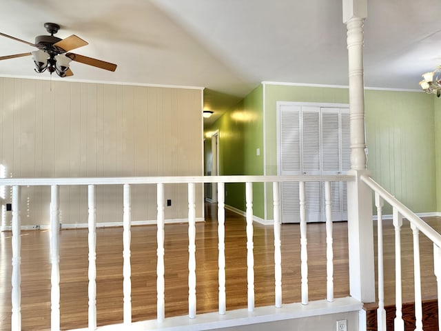 interior space with hardwood / wood-style floors, wood walls, ceiling fan with notable chandelier, crown molding, and ornate columns