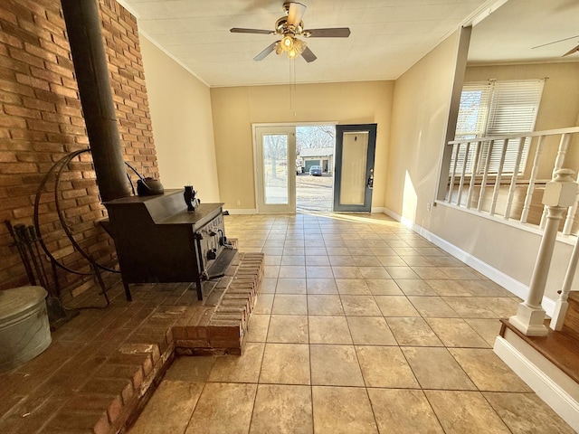 foyer with light tile patterned floors, a wood stove, ceiling fan, and ornamental molding