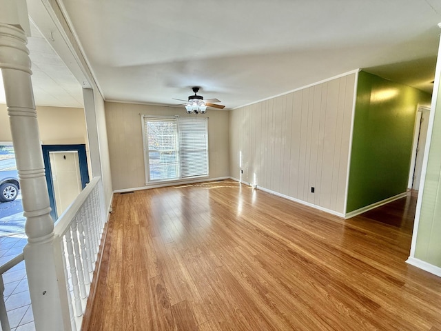 unfurnished living room featuring ceiling fan, light hardwood / wood-style floors, and wood walls