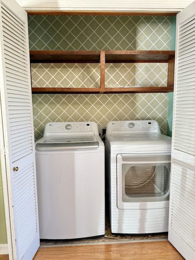 laundry room with wood-type flooring and washer and clothes dryer