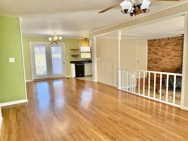 unfurnished living room with crown molding, hardwood / wood-style floors, brick wall, and ceiling fan with notable chandelier