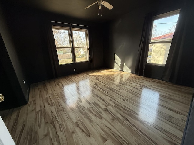 spare room featuring ceiling fan, a wealth of natural light, and light hardwood / wood-style flooring