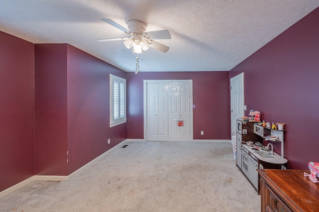 bedroom featuring a textured ceiling, light colored carpet, and ceiling fan