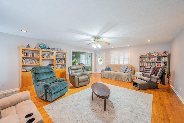 living room with ceiling fan, light hardwood / wood-style floors, and a textured ceiling