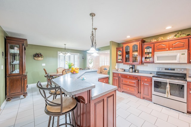 kitchen with a center island, electric stove, decorative backsplash, decorative light fixtures, and a breakfast bar area